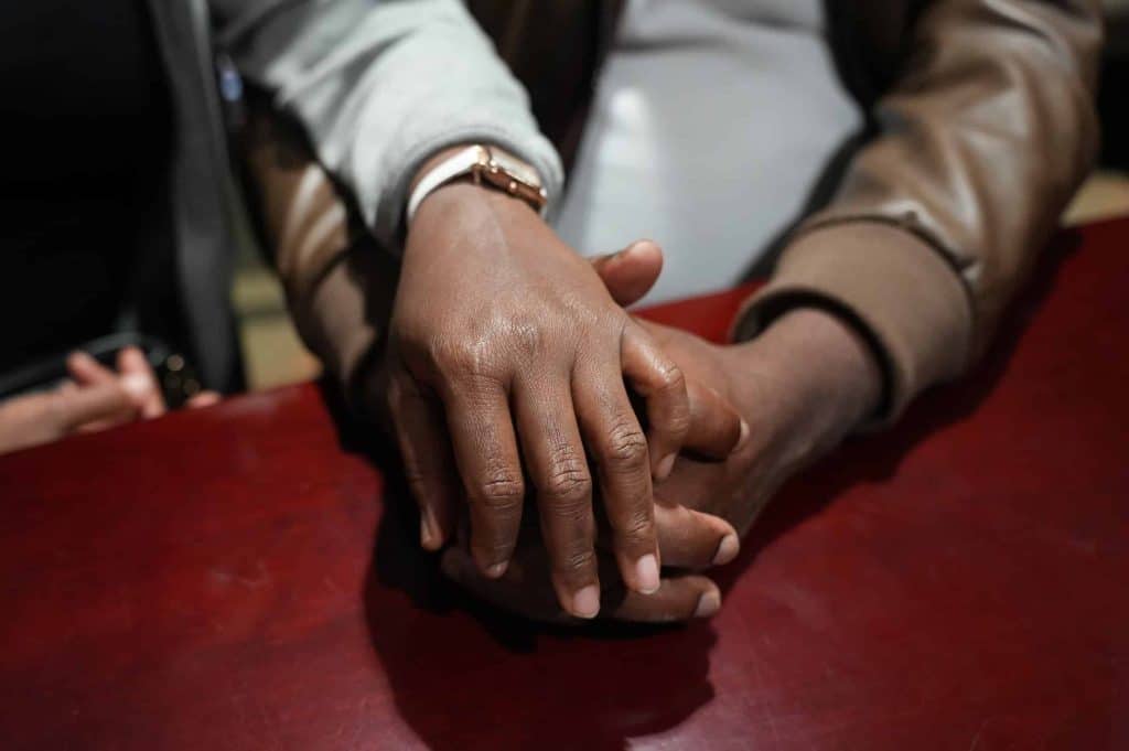 Pedro and Maria, a Haitian couple awaiting Temporary Protected Status Approval (TPS), held hands at a community meeting at the Good Samaritan Haitian Alliance Church on March 9. They are looking for ways to stay in the U.S. Photo credit: Gabriela Henriquez Stoikow.